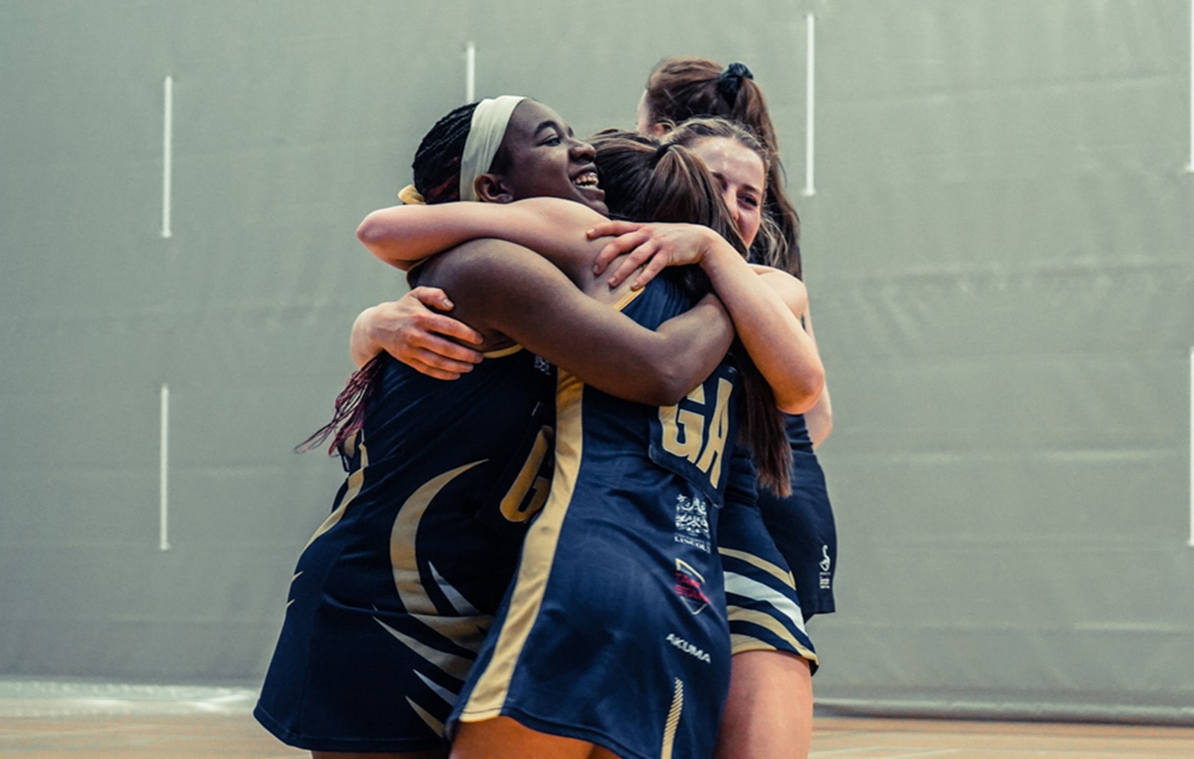 Four student netball players embracing